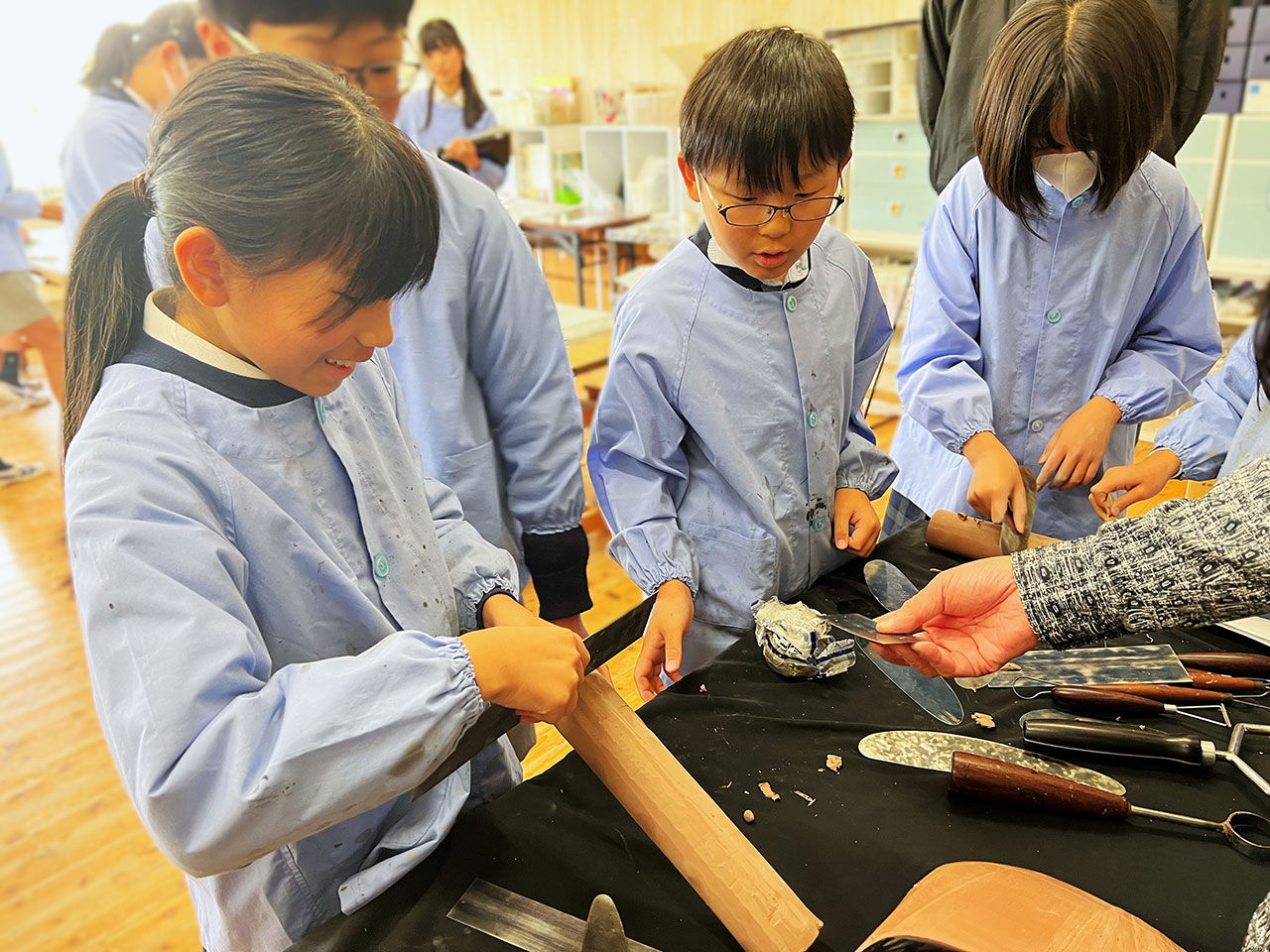 クレイモデル体験授業で工具や粘土に触れる児童